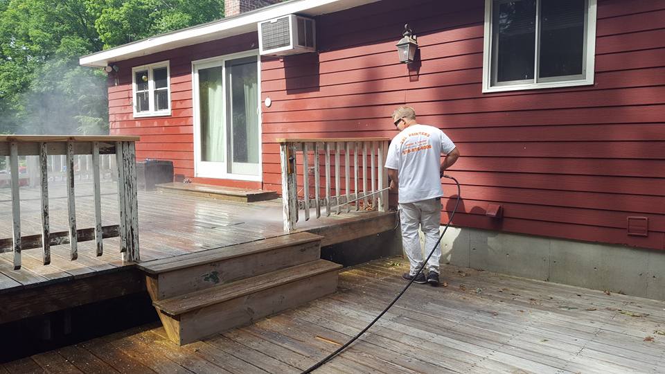Painter power washes deck in preparation for fresh coat of stain