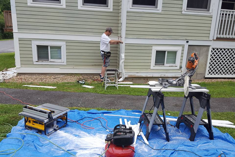 Painter trimming freshly painted white trim for side of exterior house