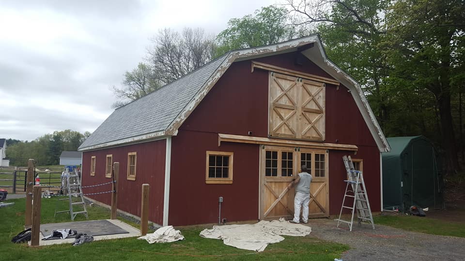 Painter prepping barn doors for fresh coat of paint
