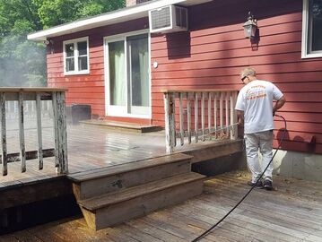 Painter power washing deck in preparation for fresh paint