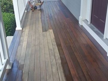 Painter applying espresso stain to sanded porch