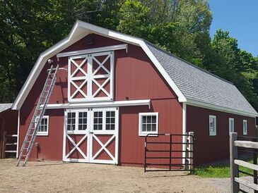 Red barn with newly painted white trim on windows and barn door